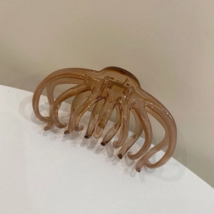Detail view of large amber hair claw clip with strong golden spring for thick hair