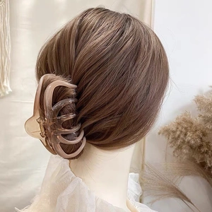 Close-up of a large milk tea brown claw clip securing a chic French bun on thick hair