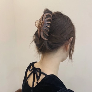 Detail of a large amber acrylic hair claw clip holding a French elegant hairstyle