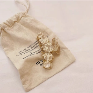 Detail of cream marbled acetate hair claw clip resting on a soft cotton drawstring bag