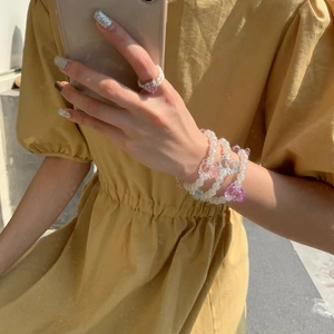 Détail de bracelets en perles d'ours et bague cœur rose portés au poignet du mannequin