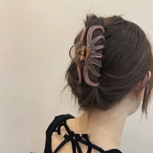 Detail of a large amber hair claw clip securing a casual French bun on thick hair
