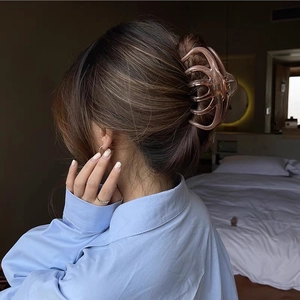 Detail of a large amber resin hair claw clip securing a low bun hairstyle for women