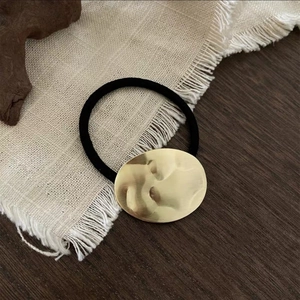 Minimalist black elastic hair tie with hammered wavy texture gold metal oval detail