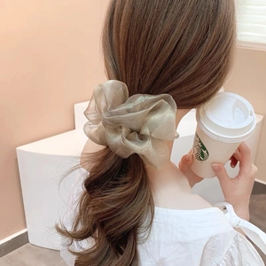 Détail du chouchou en organza or champagne avec plis soyeux sur une queue de cheval
