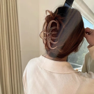 Rear view of a model wearing a large champagne resin hair claw clip for elegant styling