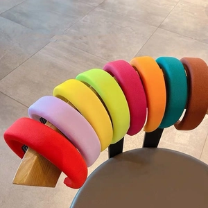 Macro view of padded fabric headbands in eight vibrant colors on a wooden stand