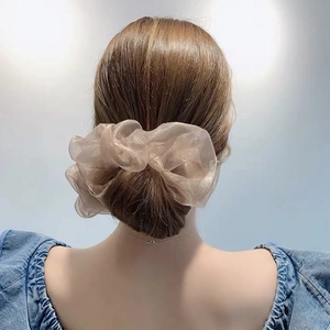 Chouchou élégant en organza doré champagne présenté sur un chignon pour un look chic