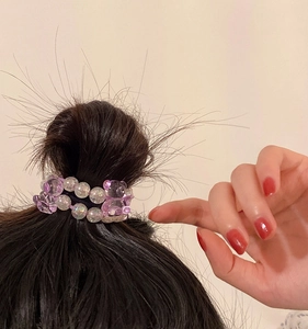 Élastique à perles ours en cristal violet porté sur un chignon haut pour jeune fille