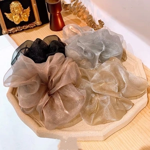 Détail de chouchous en organza scintillant en quatre couleurs sur plateau en pierre