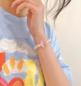 Gros plan d'un pendentif ours rose et perles sur un bracelet élastique pour cheveux
