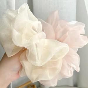 Gros plan de chouchous en organza surdimensionnés en blanc crème et rose doux plissés