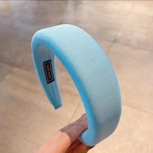 Macro detail of sky blue padded headband showing satin texture and hand made label