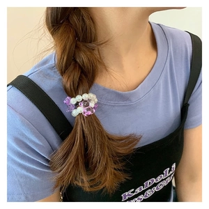Détail d'un élastique à perles avec ours en cristal violet et perles sur une tresse