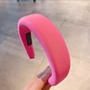 Close-up of bright pink padded sponge headband with handmade label and knit texture