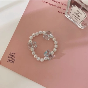 Détail d'élastique à perles avec breloques d'ours et perles irisées sur fond rose
