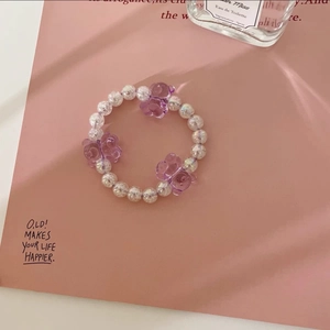 Gros plan sur bracelet chouchou perlé avec ours en cristal violet et perles blanches