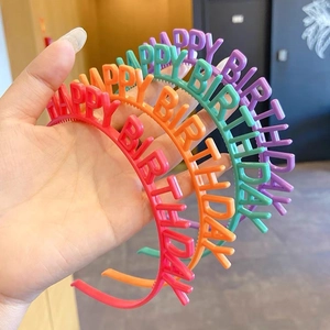 Détail de quatre serre-têtes Joyeux Anniversaire en rouge, orange, vert et violet