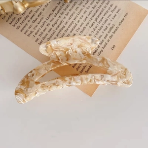 Detalle de una elegante pinza para el pelo en acetato jaspeado sobre papel antiguo