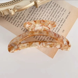 Primer plano de pinza de pelo de acetato con patrón de carey sobre libros antiguos