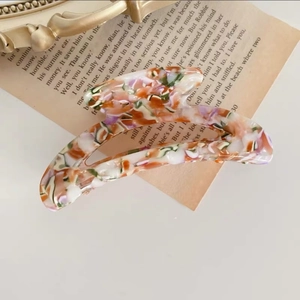 Detalle de pinza para el pelo con patrón de mármol sobre fondo de página de libro vintage