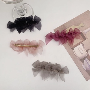 Close-up of four colored organza bow hair clips with gold metal duckbill fasteners