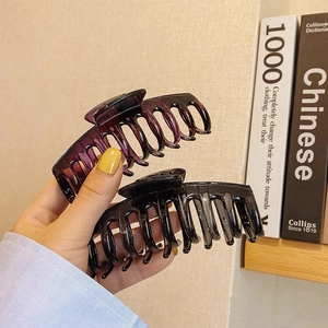 Grandes pinces à cheveux en résine noir et violet, tenues à la main pour coiffures élégantes