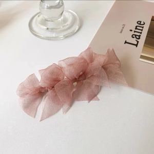 Detailed close-up of a pink sparkling organza bow hair clip on a clean background