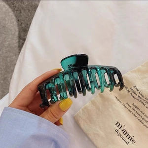 Gros plan sur la grande pince à cheveux vert foncé translucide en acétate poli brillant