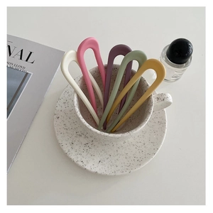 Set of five matte candy-colored U-shaped hair forks in a ceramic cup with magazine