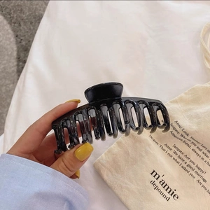Gros plan sur une grande pince à cheveux noir brillant en plastique durable et lisse