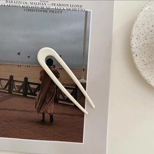 Close-up of minimalist cream U-shaped hair pin on a fashion magazine background