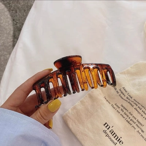 Détail d'une grande pince à cheveux ambrée avec motif écaille de tortue à la main