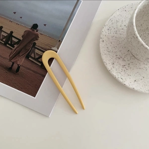 Close-up of yellow U-shaped hair pin for minimalist styling on a creative background