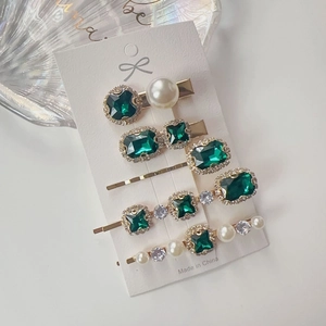 Detailed macro view of 5-piece emerald rhinestone and pearl hair clips set