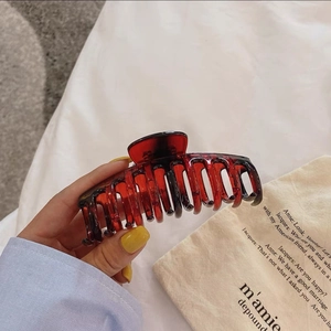 Gros plan d'une grande pince à cheveux en résine bordeaux translucide à dents multiples
