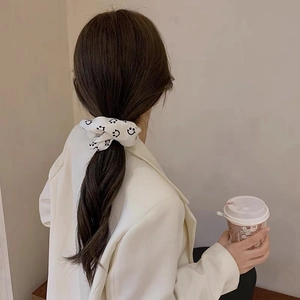Elegant white satin scrunchie with black smiley faces worn on a low ponytail