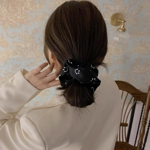 Elegant black satin scrunchie with white smiley face patterns on a model's ponytail