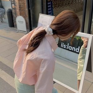 Détail du chouchou blanc à motif smiley avec chemise rose et pantalon vert