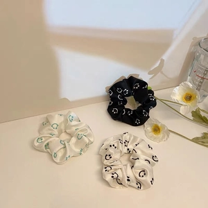 Three-piece set of satin scrunchies with smiling face patterns in white and black