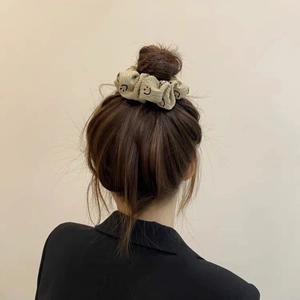 Gros plan d'un chouchou beige à motif smiley porté sur un chignon élégant