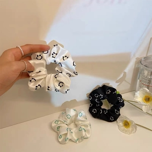 Detailed texture of satin scrunchies with minimalist smiley patterns and silk-like shine