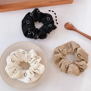 Détail de trois chouchous texturés avec motifs de sourires posés sur une assiette blanche