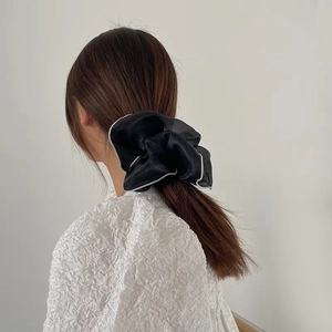 Detail of oversized black organza scrunchie with white contrast edge on ponytail