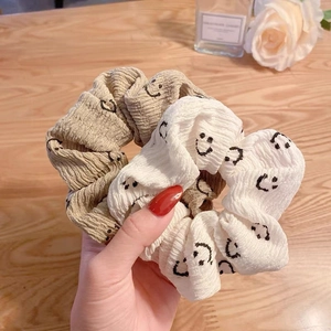 Chouchous imprimés visages souriants en beige et blanc posés sur une table en bois