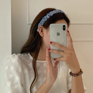 Detail of light blue pleated satin headband with elegant ruched fabric texture on model