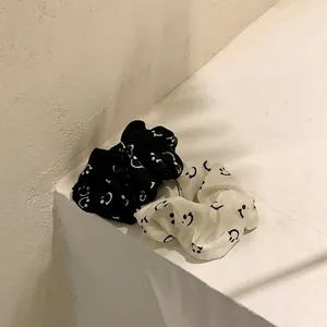 Two-piece black and white smiley face scrunchies set with a minimalist chiffon design