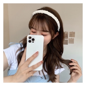 Close-up detail of the white pleated scrunchie headband worn by a female model