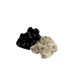 Two-piece black and white satin scrunchies with minimalist smiley face prints for women
