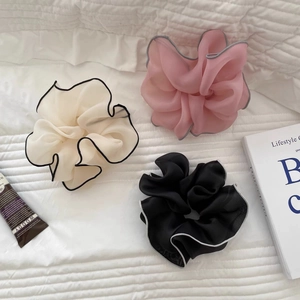 Macro detail of large organza scrunchies in pink, white, and black with contrast edging